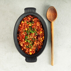 Mexican Chili with Corn Chips and Wooden Spoon on Light Background