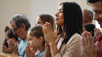 People of different ages and ethnicities are joining hands in prayer at church, diverse group of men, women and children seeking spiritual guidance together and finding comfort in shared faith