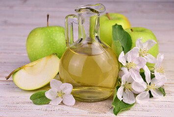 Apple cider vinegar in a small decanter and green apples. Close-up.
