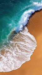 Vertical top view of wave hitting golden beach with foam trails creating layered shoreline effect in crisp aerial ocean photography for high resolution travel wallpaper