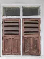 Antique Asian wooden shutters covered in brown and white cement walls