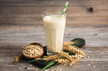 Oat milk in a glass on the wooden table.  Non dairy, plant based alternative milk, vegetarian,...