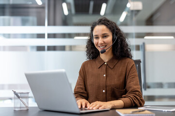 Support service worker working inside office with laptop and headset. Businesswoman using laptop...