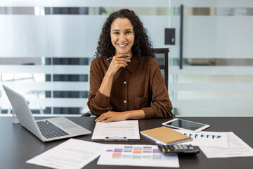 Portrait of a successful businesswoman, financier, accountant. Company employee looking at the camera, working with documents, papers and reports.