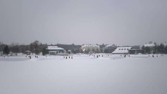 Gravenhurst wharf covered in snow and ice in winter, with buildings and trees in the background