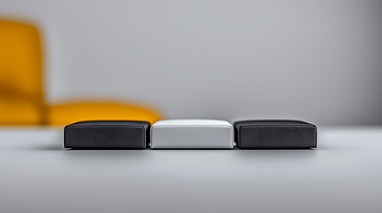 Minimalist arrangement of three cushions in contrasting colors on a sleek table with blurred background