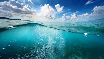 half underwater shot of the sea with cloudy sky turquoise water sun glare and bubbles forming a calming ocean landscape
