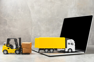 Yellow forklift on bright textured background. Logistics concept. Logistics and supply chain management for online shopping concept. Delivery of goods or products to the store worldwide. Cardboard box