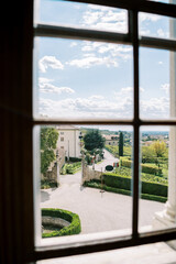 View from the window of the road and trimmed bushes in the garden near the house