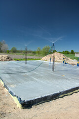 Budowa domu, pielęgnacja świeżej płyty fundamentowej poprzez zraszanie betonu wodą © gpmax