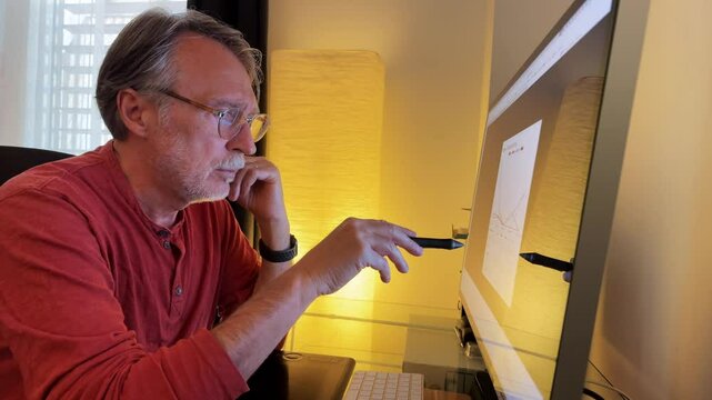 Senior man at computer looking at data at home