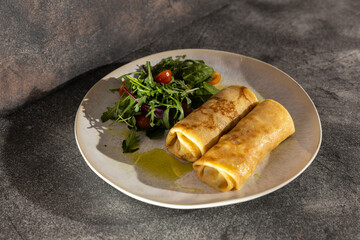 Fresh crepes served with a vibrant salad of arugula, cherry tomatoes, and red onions, drizzled with olive oil on a rustic plate. Perfect for food styling!