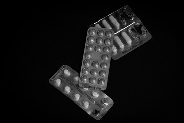Black and white photo of pills in blister packs on a black background