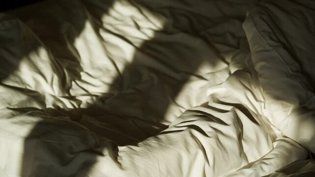 shadow on bed in bedroom.
Unmade bed on sunny day.
Cozy room
