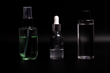 Three types of cosmetic bottles of different types and colors on a black background