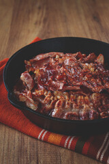 Crispy bacon, on a cast-iron skillet, on a wooden table, rustic style, no people