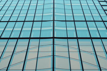 Fototapeta premium A close-up view of a modern skyscraper's reflective glass facade with grid pattern