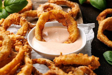 Deep fried onion rings on wooden board with sauce