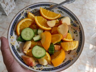 Vegetarian fruits mix salad with ingredients, slices of apple, orange, and cucumber.  