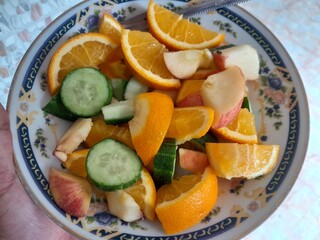 Vegetarian fruits mix salad with ingredients, slices of apple, orange, and cucumber.  