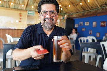 Latino man paying for beer with credit card in caribbean bar