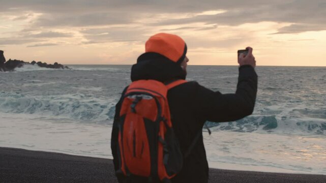 Man Exploring and Photographing Iceland&rsquo;s Black Sand Beach