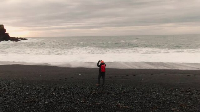 Man Exploring and Photographing Iceland&rsquo;s Black Sand Beach