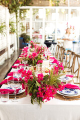 A set festive table in the open air. The table is decorated with candles and flowers
