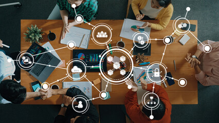 A top-down view of a collaborative business meeting featuring a team analyzing charts and data....