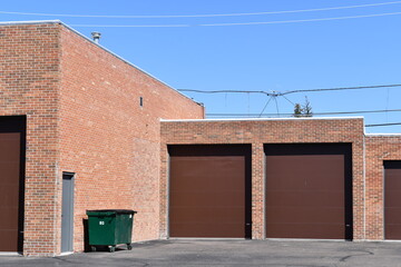 Garage doors on industrial building. Green dumpster against wall.