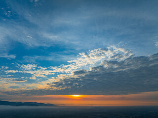 A breathtaking sunrise illuminates a small village nestled among lush green fields and karst mountains, with vibrant clouds filling the sky. The harmony of rural life set dramatic natural formations.