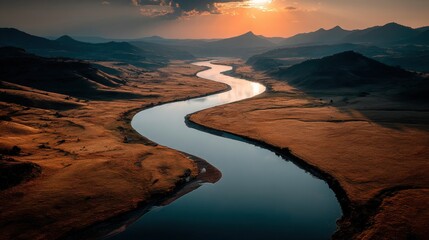 Fototapeta premium Aerial view of a winding river flowing through a canyon valley under a cloudy sky at sunset