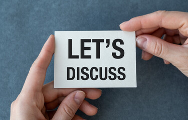 A hand holding a white card that says Let's discuss