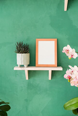 white small frame mockup on shelf with decoration objects, rustic green wall