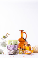 Bright composition with set of natural eco spa and wellness products such as handmade soap, essential oils, Himalaya salt, massage brushes and fresh green twigs on white background, selective focus.