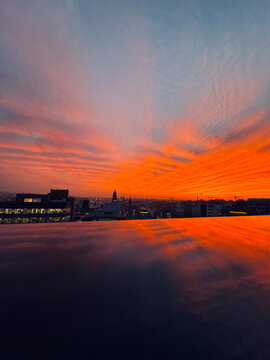 View of the city of Porto at sunset, reflected in the water. Dramatic sky with shades of blue, orange and red. Portugal