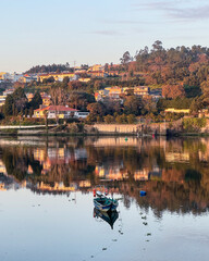 Obraz premium Traditional boat on the Douro River at golden sunset in Avintes, Vila Nova de Gaia, with view toward Gondomar