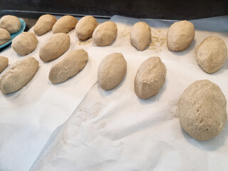 Uncooked Cepelinai, the popular Lithuanian potato dish, are shown prepared on baking paper. These large, oval shapes are handmade, highlighting traditional Lithuanian cuisine and the process of making