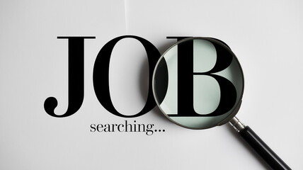 Magnifying glass over the word JOB, symbolizing job search and opportunities, simple and direct visual concept