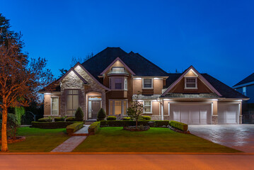 Two story stucco luxury house with nice Spring blossom landscape at night in Vancouver, Canada, North America. April 2025.