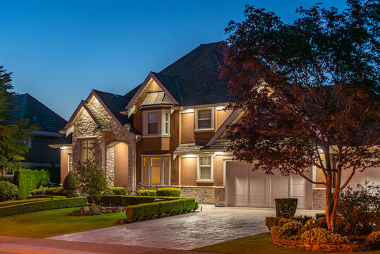 Two story stucco luxury house with nice Spring blossom landscape at night in Vancouver, Canada, North America. April 2025.
