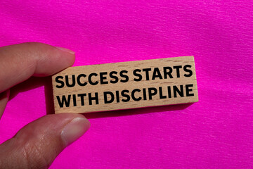 Success starts with discipline message written on wooden block on pink background. Conceptual success starts with discipline symbol. Copy space.
