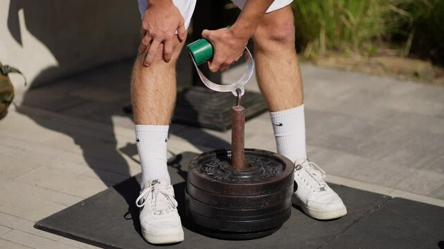 Athlete preparing for grip strength training, lifting heavy weights with special handle outdoors.