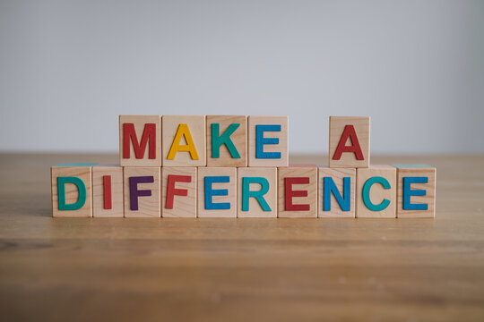 Wooden blocks spelling Make a Difference on wood table, showcasing positive message, inspiration, and motivation