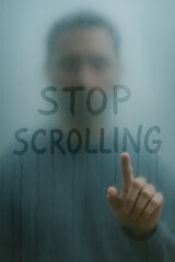 man tracing the words "STOP SCROLLING" with his fingers on fogged glas