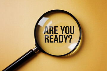 Magnifying glass on yellow background, showcasing "Are you ready?" text, symbolizing preparation, opportunity, and a call to action