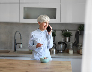 businesswoman busy home woman mature kitchen morning hydration mobile call smartphone phone healthy...