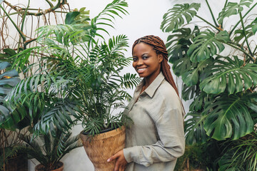 A woman gracefully poses with a bright houseplant surrounded by beautiful lush greenery