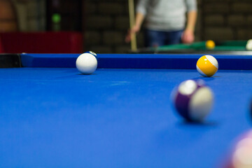 8-ball pool in progress, balls are on blue table cloth