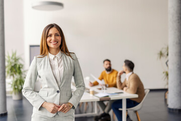 Portrait of professional businesswoman in suit standing at corporate firm in a boardroom during the...